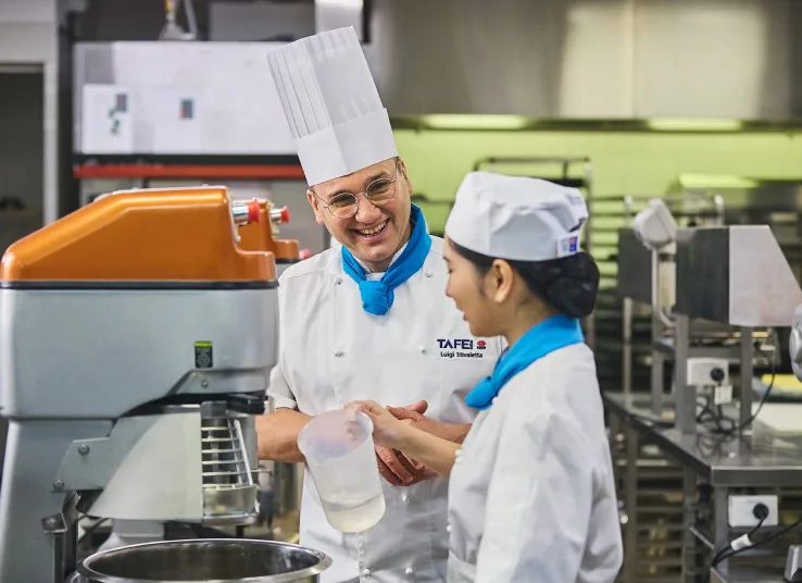 Giảng viên hướng dẫn sinh viên thực hành trong bếp công nghiệp
